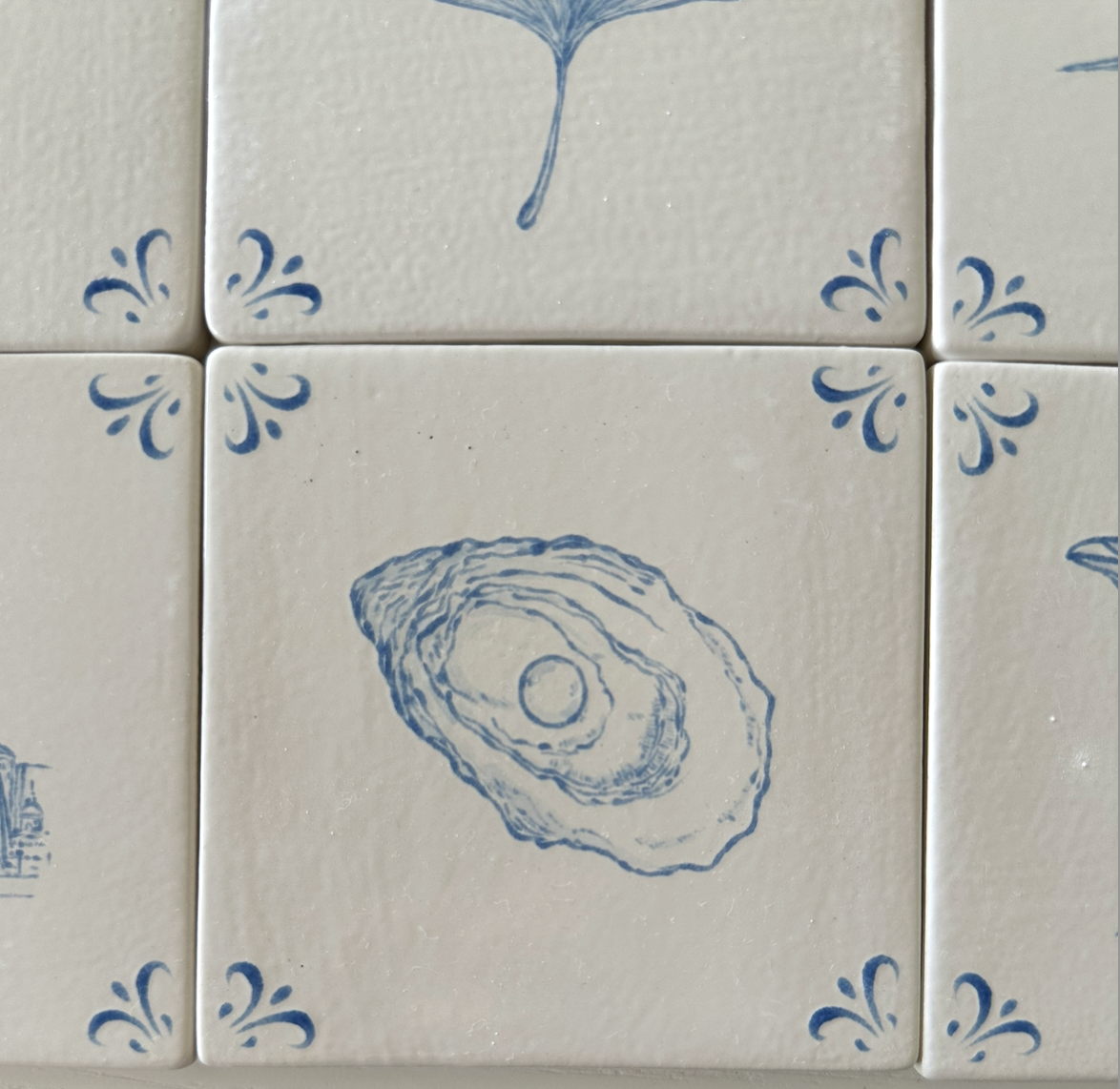 Close-up of the hand-painted oyster motif on an Akka Home Delft tile